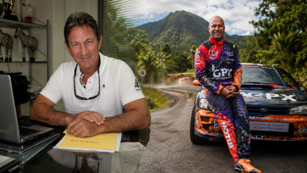 Bernard Levalois à gauche et Simon Jean-Joseph à droite devant une voiture de rallye, avec une route montagneuse martiniquaise en arrière-plan.